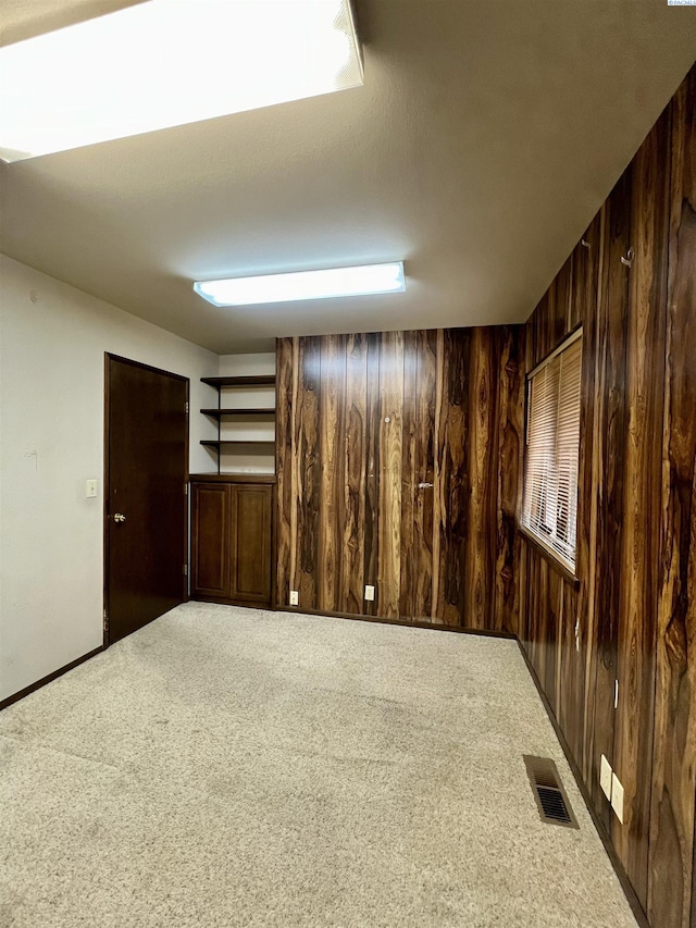 carpeted empty room featuring wooden walls