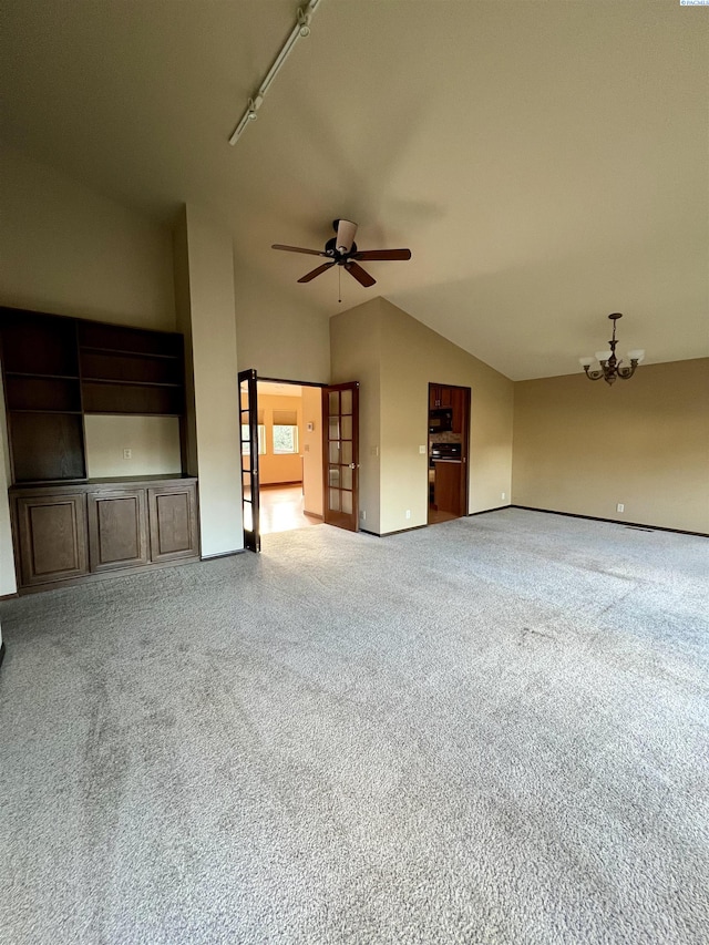 unfurnished living room with lofted ceiling, carpet floors, ceiling fan with notable chandelier, and track lighting