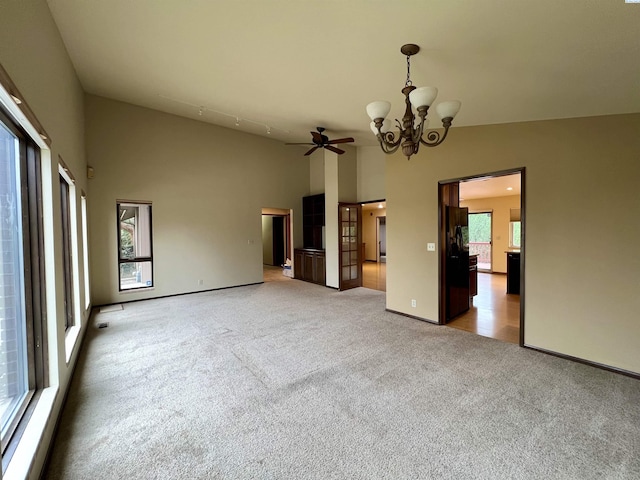 spare room featuring high vaulted ceiling, light carpet, and a chandelier