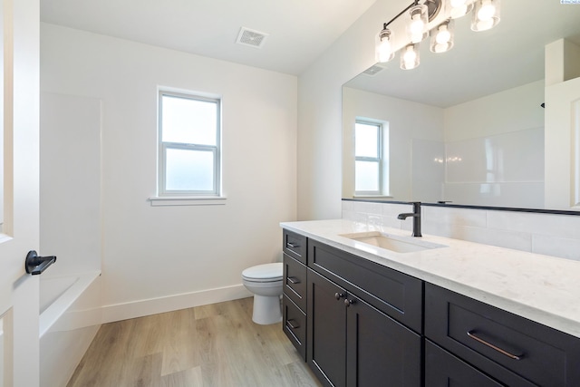 full bath featuring baseboards, visible vents, toilet, wood finished floors, and backsplash