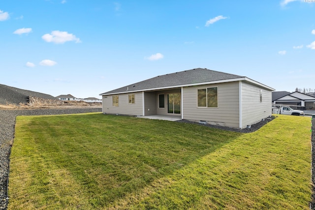 rear view of house featuring crawl space, a patio area, a lawn, and roof with shingles