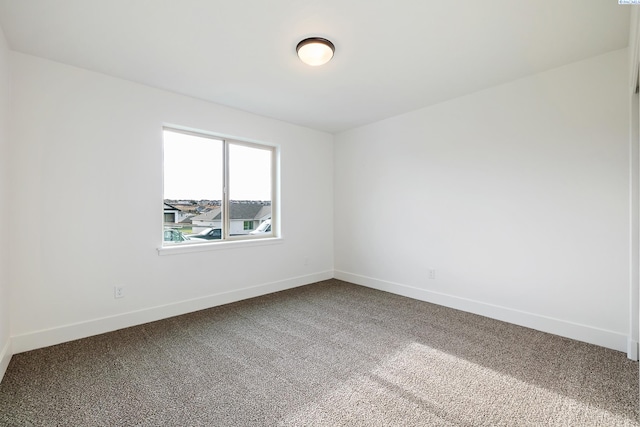 spare room featuring carpet and baseboards