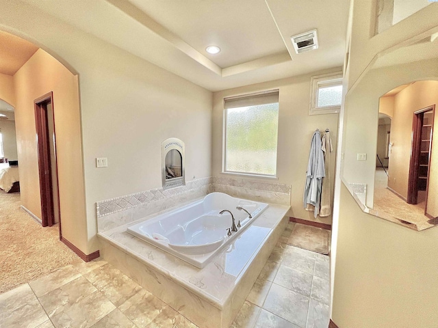 bathroom with tiled bath and a raised ceiling