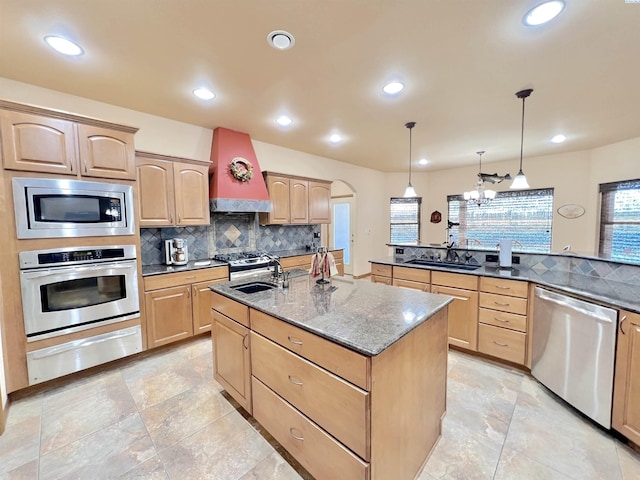 kitchen featuring premium range hood, sink, appliances with stainless steel finishes, an island with sink, and pendant lighting