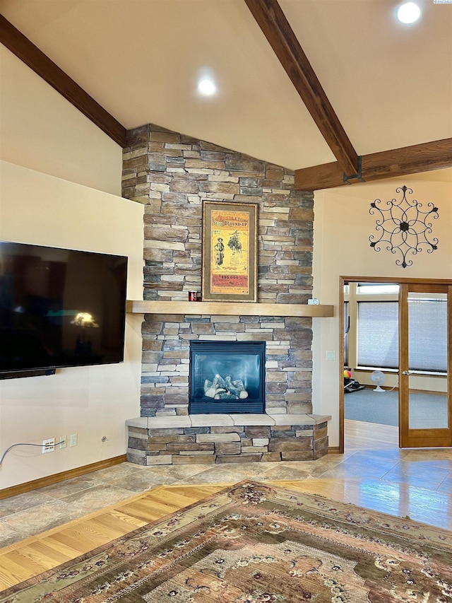 living room with hardwood / wood-style floors, a stone fireplace, and lofted ceiling with beams