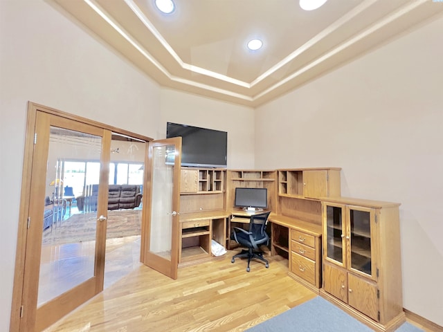 office area featuring a tray ceiling, light hardwood / wood-style floors, and french doors