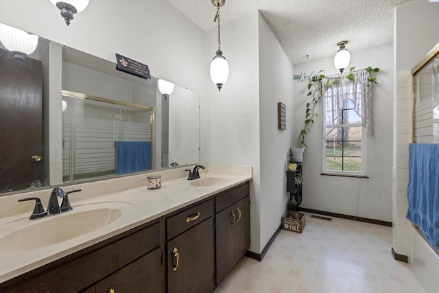 697 Conrad Rd, Touchet, WA 99360 - bathroom with double vanity, a shower with shower door, tile patterned floors, baseboards, and a textured ceiling