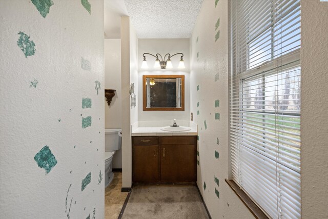 697 Conrad Rd, Touchet, WA 99360 - bathroom with a textured wall, vanity, toilet, a textured ceiling, and baseboards