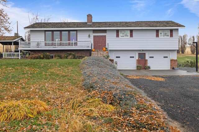 697 Conrad Rd, Touchet, WA 99360 - view of front of home with an attached garage, a chimney, driveway, a front lawn, and brick siding