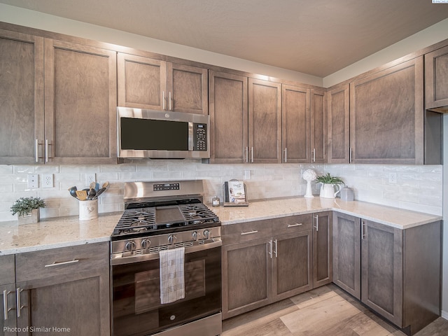 kitchen with stainless steel appliances, tasteful backsplash, and light stone countertops