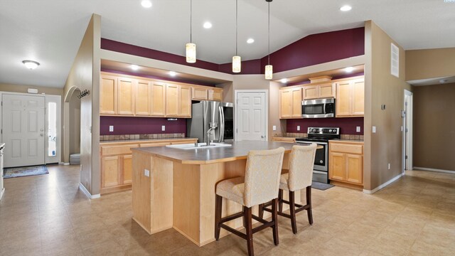 5706 Wrigley Dr, Pasco, WA 99301 - kitchen with appliances with stainless steel finishes, light brown cabinets, vaulted ceiling, a sink, and a kitchen island with sink