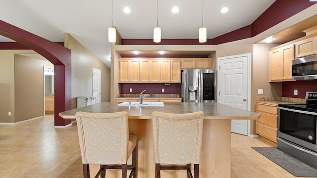 5706 Wrigley Dr, Pasco, WA 99301 - kitchen featuring appliances with stainless steel finishes, a sink, light brown cabinetry, arched walkways, and a breakfast bar area