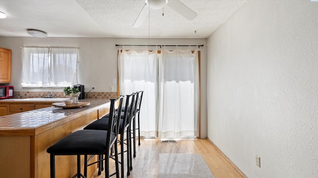 1707 S Fruitland St, Kennewick, WA 99337 - dining area with light wood-style flooring, a textured wall, ceiling fan, and a textured ceiling