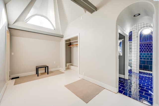 interior space with tile patterned flooring and lofted ceiling with beams