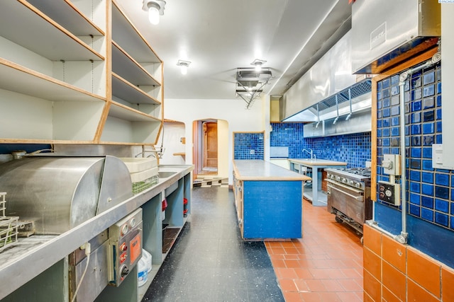 kitchen featuring sink, dark tile patterned floors, a center island, tasteful backsplash, and high end stainless steel range