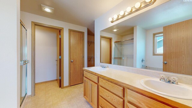 4613 Atlanta Ln, Pasco, WA 99301 - bathroom featuring a shower stall, double vanity, tile patterned floors, a walk in closet, and baseboards