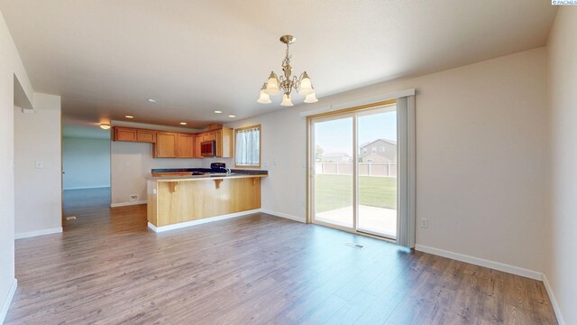 4613 Atlanta Ln, Pasco, WA 99301 - kitchen with stainless steel microwave, a chandelier, wood finished floors, a peninsula, and baseboards
