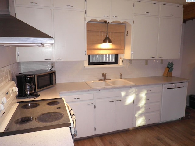 kitchen with sink, white appliances, wall chimney range hood, white cabinets, and decorative light fixtures