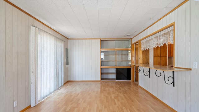 2111 W 20th Ave, Kennewick, WA 99337 - empty room featuring wood walls, wood finished floors, ornamental molding, plenty of natural light, and electric panel
