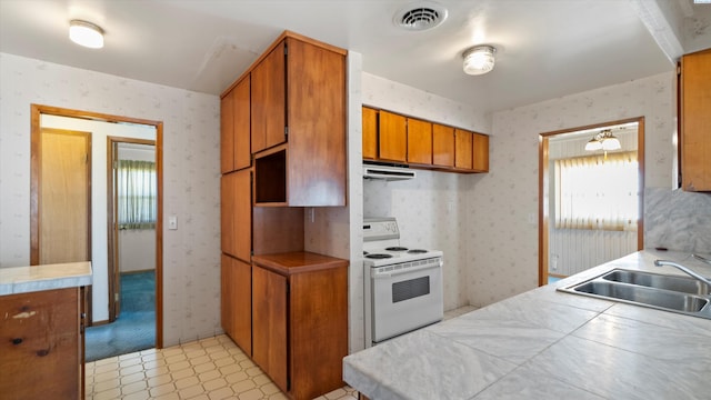 2111 W 20th Ave, Kennewick, WA 99337 - kitchen with white electric range oven, wallpapered walls, brown cabinetry, range hood, and light flooring