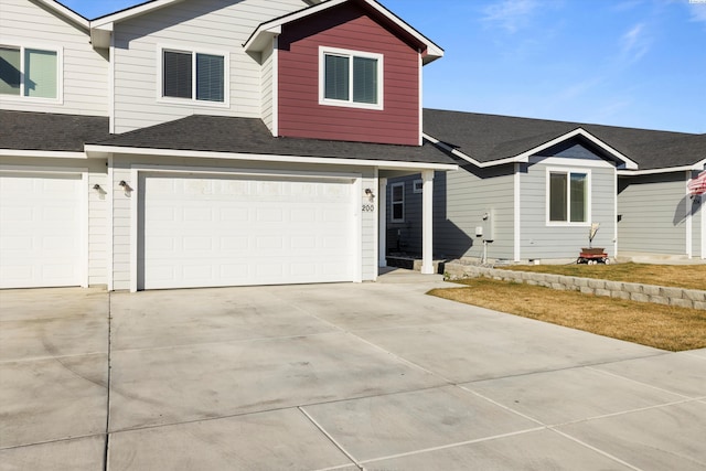 view of front of home featuring an attached garage, a shingled roof, and driveway