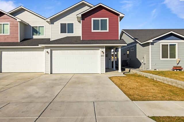 view of front of home with an attached garage, concrete driveway, a front yard, and a shingled roof