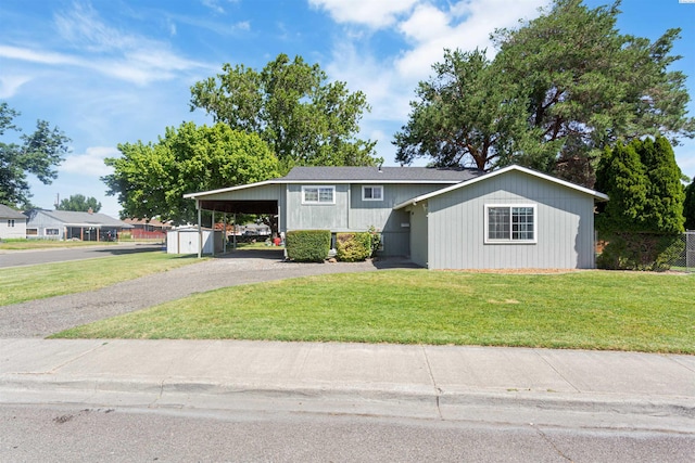1621 S Fruitland St, Kennewick, WA 99337 - view of front of home with asphalt driveway, an attached carport, a front lawn, and a storage unit