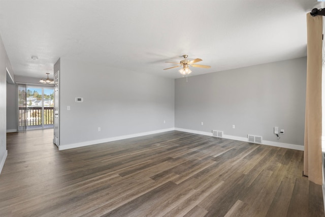 empty room with dark hardwood / wood-style flooring and ceiling fan with notable chandelier