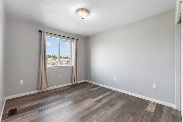 empty room featuring dark hardwood / wood-style flooring and a textured ceiling