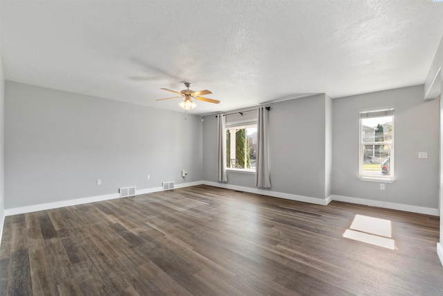 unfurnished room featuring a healthy amount of sunlight, dark wood-type flooring, and a textured ceiling