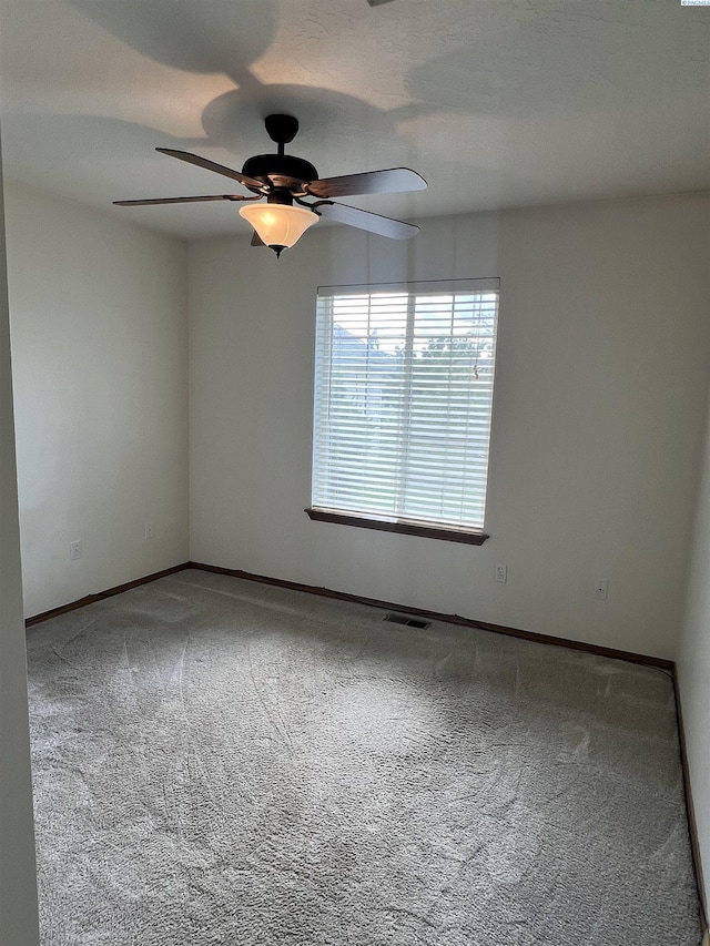 carpeted spare room with a ceiling fan and baseboards