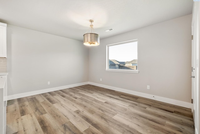 spare room featuring visible vents, light wood-style flooring, and baseboards