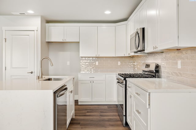 kitchen featuring stainless steel appliances, dark wood-style flooring, a sink, white cabinets, and decorative backsplash