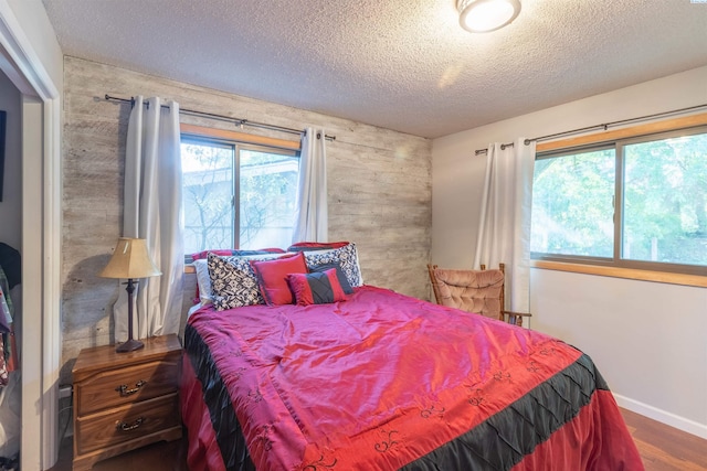 625 SW Dawnview Ct, Pullman, WA 99163 - bedroom with a textured ceiling, wood finished floors, wood walls, baseboards, and an accent wall