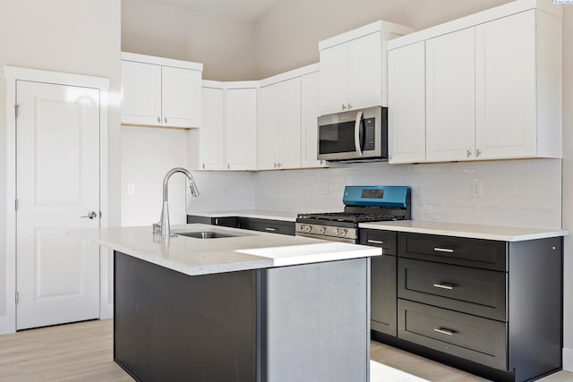 6435 W 30th Pl, Kennewick, WA 99338 - kitchen featuring stainless steel appliances, white cabinets, backsplash, light wood-style flooring, and an island with sink