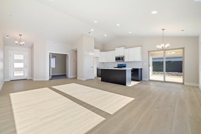6435 W 30th Pl, Kennewick, WA 99338 - kitchen featuring a chandelier, stainless steel microwave, open floor plan, stove, and high vaulted ceiling