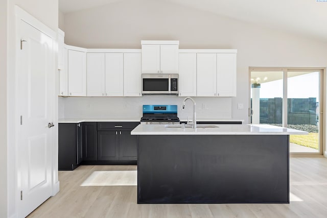 6435 W 30th Pl, Kennewick, WA 99338 - kitchen with stainless steel microwave, gas stove, light countertops, light wood-style floors, and white cabinets