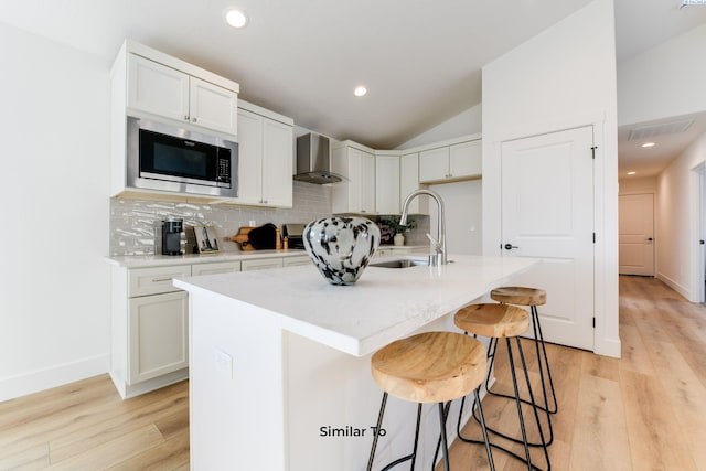 kitchen featuring wall chimney exhaust hood, built in microwave, a sink, backsplash, and lofted ceiling