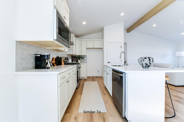 kitchen with stainless steel appliances, a sink, light wood-style flooring, a breakfast bar area, and tasteful backsplash