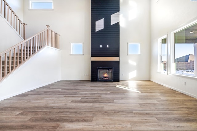 unfurnished living room with a high ceiling, a large fireplace, and light hardwood / wood-style floors