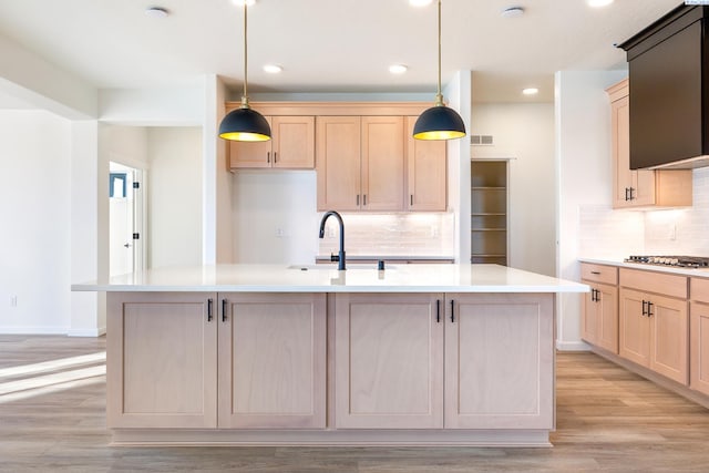 kitchen with pendant lighting, an island with sink, and light brown cabinets