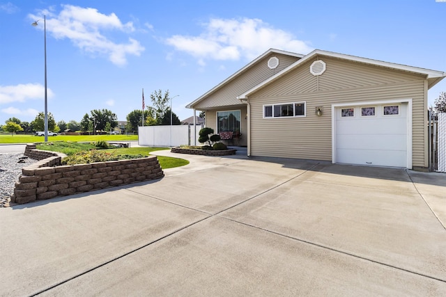 view of front facade featuring driveway, an attached garage, and fence