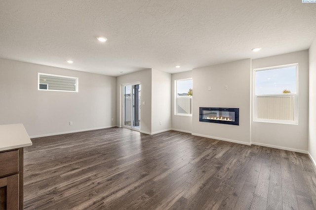 704 S Zeelar St, Kennewick, WA 99336 - unfurnished living room featuring a glass covered fireplace, dark wood-style floors, recessed lighting, baseboards, and a textured ceiling