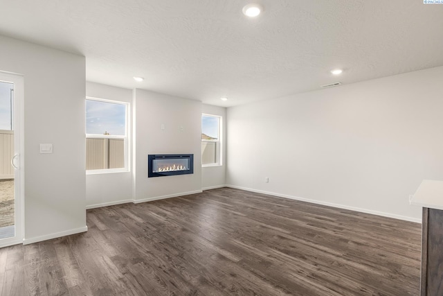 704 S Zeelar St, Kennewick, WA 99336 - unfurnished living room featuring a glass covered fireplace, dark wood finished floors, baseboards, recessed lighting, and a textured ceiling