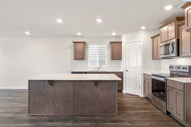 704 S Zeelar St, Kennewick, WA 99336 - kitchen featuring appliances with stainless steel finishes, a sink, a center island, dark wood-style flooring, and a breakfast bar