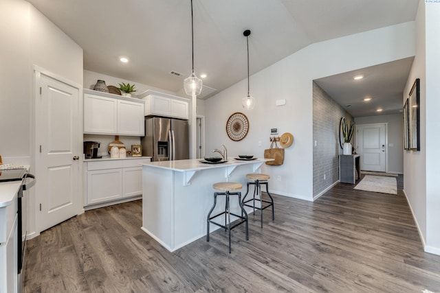 kitchen featuring a kitchen island with sink, hanging light fixtures, stainless steel fridge, and white cabinets