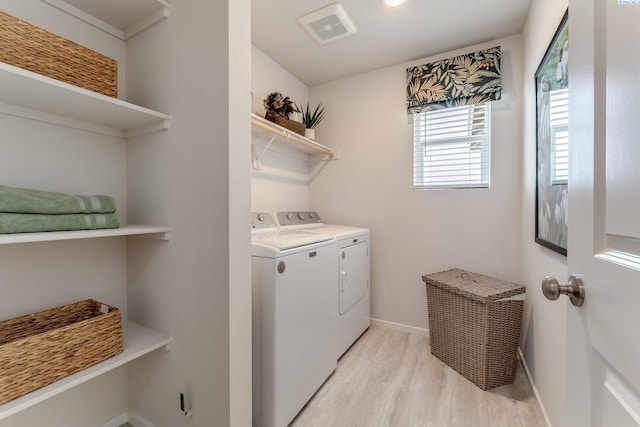 laundry area with washing machine and clothes dryer and light wood-type flooring