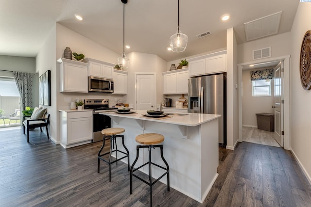 kitchen with white cabinetry, appliances with stainless steel finishes, a center island with sink, and decorative light fixtures