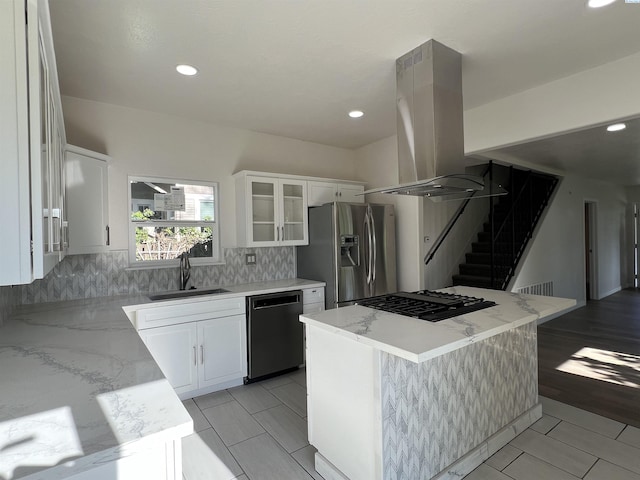 kitchen featuring island exhaust hood, a sink, black appliances, glass insert cabinets, and white cabinetry
