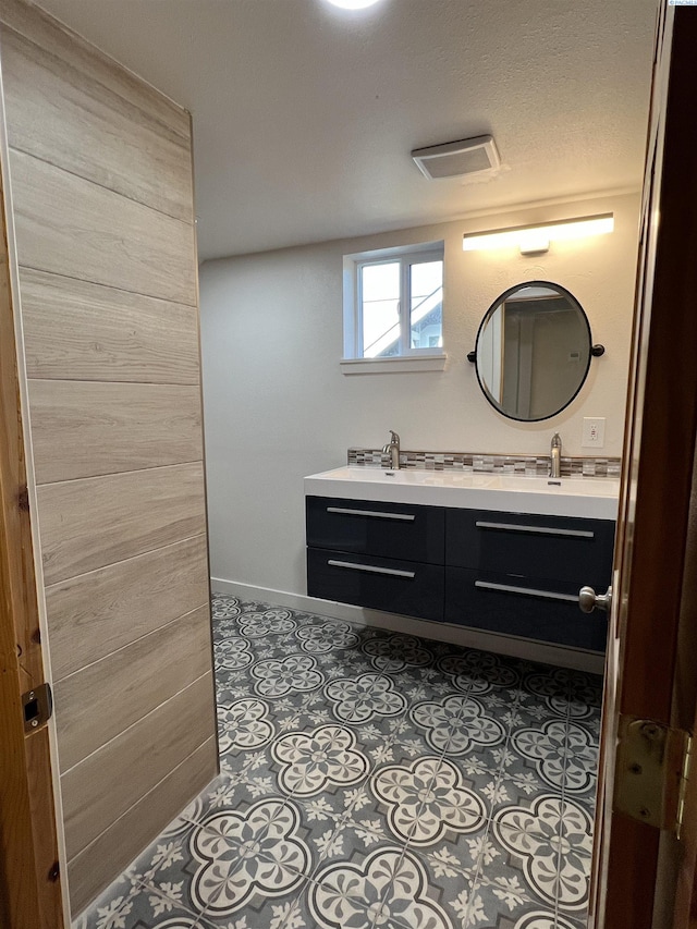 full bath featuring visible vents, double vanity, a sink, and baseboards